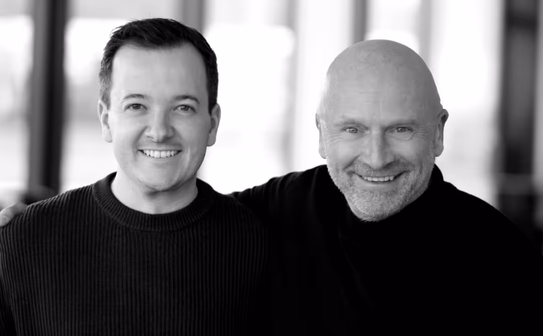 Zwei lächelnde Männer, der linke ist Stefan Schwarz mit dunklem Haar und der ältere mit Glatze und Bart ist Marcus Linnepe. Beide posieren nah beieinander in einem hellen Raum.